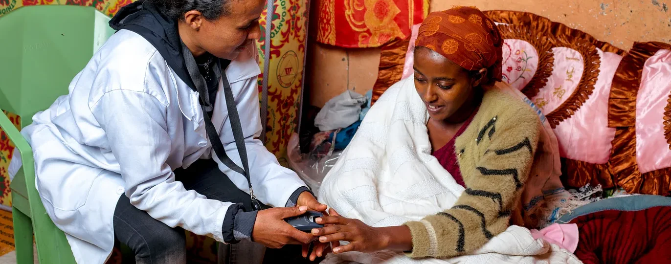 A health extension worker uses a Simprints fingerprint scanner to check on a client